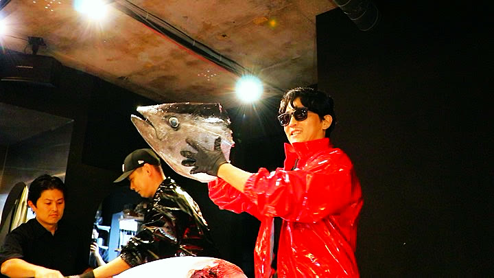 The tuna head held up to the room after it is cut off